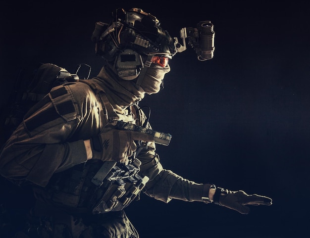 Army special operations soldier security service fighter\
commando shooter equipped modern ammunition wearing combat helmet\
mask and glasses carefully sneaking in darkness with handgun in\
hand