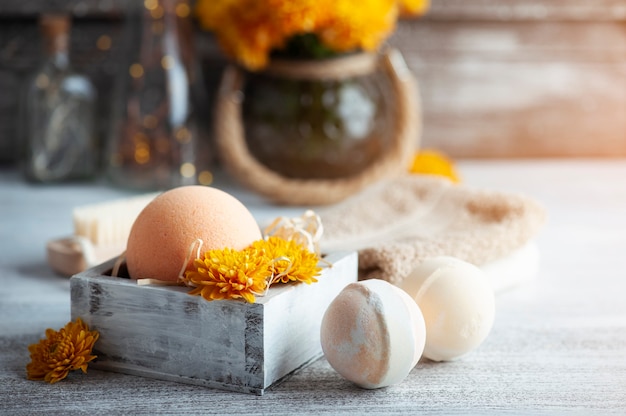 Aroma bath bombs in spa composition with orange flowers and brush. Aromatherapy arrangement, zen still life with lights