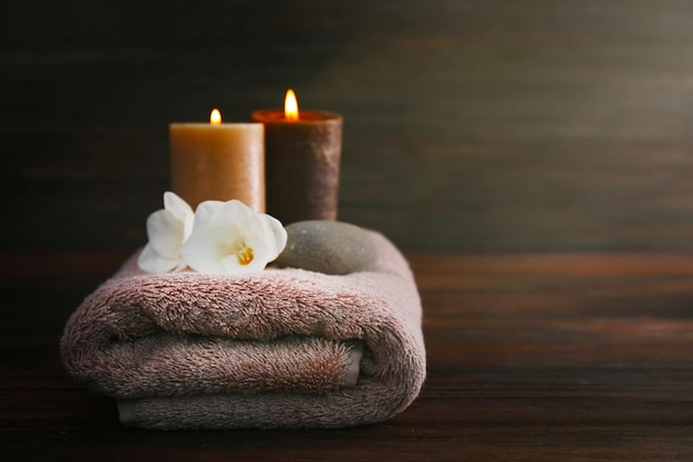 Aroma candles towel and beautiful flowers on wooden background