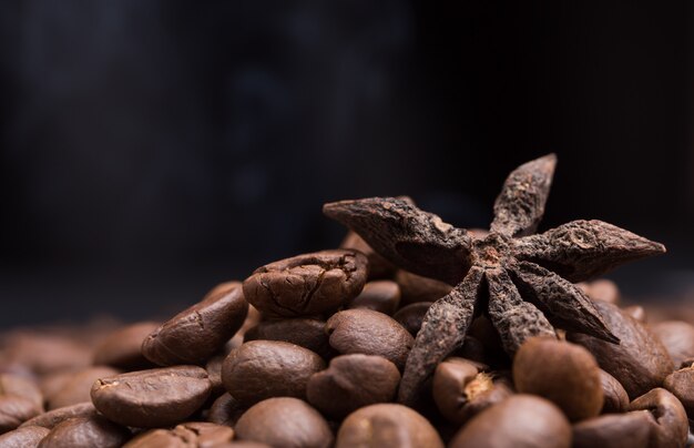 Foto aroma gebrande koffiebonen en steranijs met rook stijgt op donker