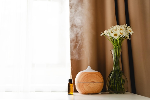 Foto concetto di aromaterapia diffusore di olio aromatico sul tavolo contro la finestra deodorante per ambienti diffusore di aromi ad ultrasuoni per la casa