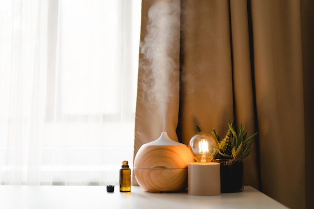 Aromatherapy concept Aroma oil diffuser on the table against the window Air freshener Ultrasonic aroma diffuser for home