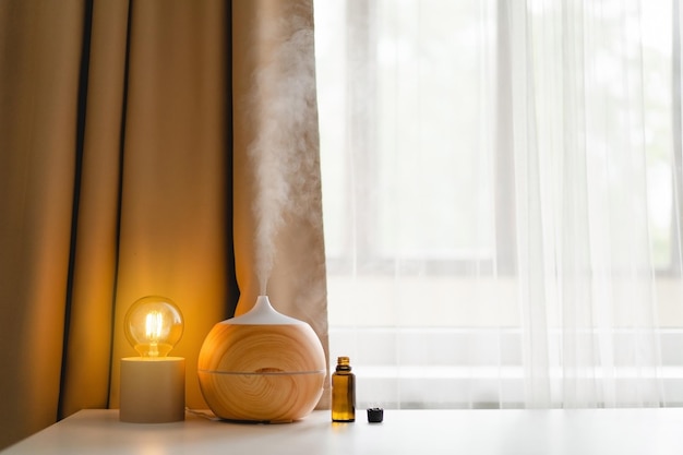 Aromatherapy concept Aroma oil diffuser on the table against the window Air freshener Ultrasonic aroma diffuser for home