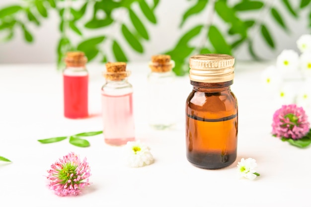 Aromatherapy oil in a brown bottle and floral extracts in transparent bottles with wildflowers