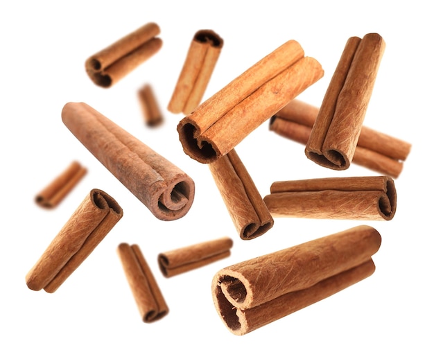 Aromatic cinnamon sticks falling on white background