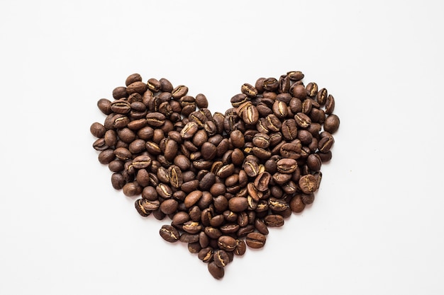 Chicchi di caffè aromatici a forma di cuore su sfondo bianco