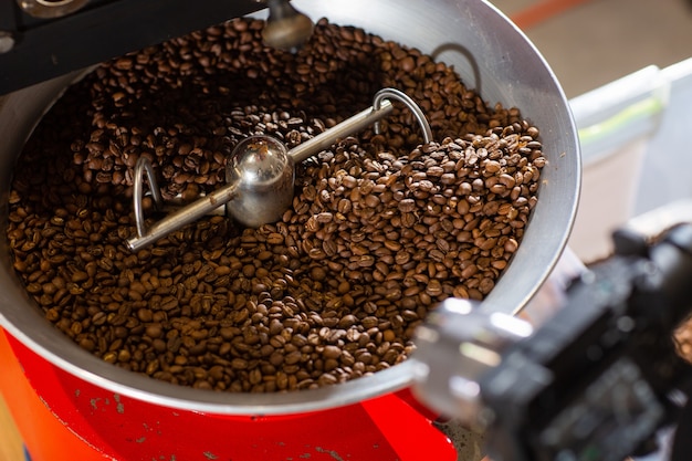 Aromatic coffee beans situating in modern equipment with grain chiller. Industry concept. a modern machine used for roasting beans. coffee roaster being poured into the cooling cylinder.