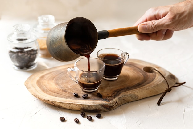 Aromatic coffee pouring from a finjan coffee pot into a glass cup