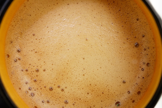 Aromatic coffee with foam from a capsule coffee machine in a cup, top view