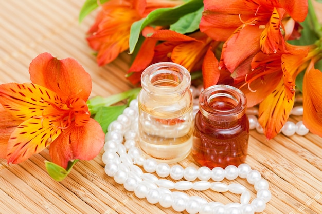 Olio essenziale aromatico in piccole bottiglie di vetro, fiori di alstroemeria e perle di perle