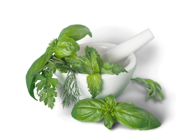 Aromatic green herbs in ceramic mortar on table