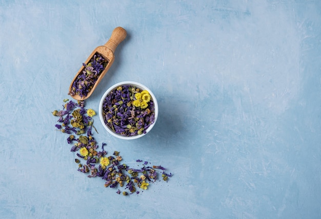 Aromatic herbal dry tea lavender and chamomile loose near white cup on blue wood table