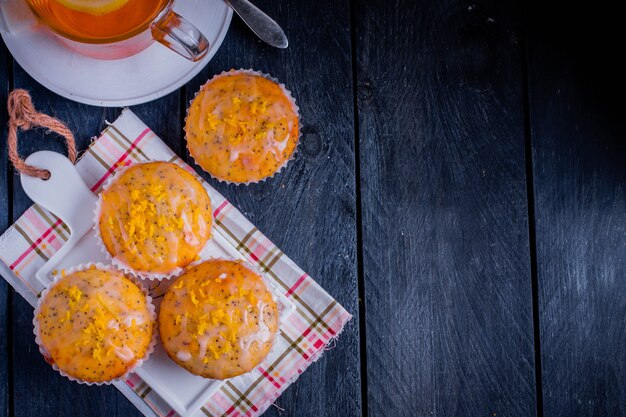 Ароматные домашние кексы с лимоном и маком с чашкой чая на сером фоне