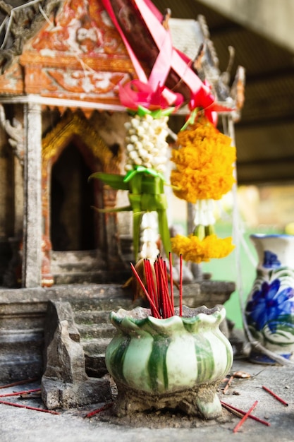 Фото Ароматический ладан красные палочки в глиняном горшке на фоне небольшого храма для молитвы будды