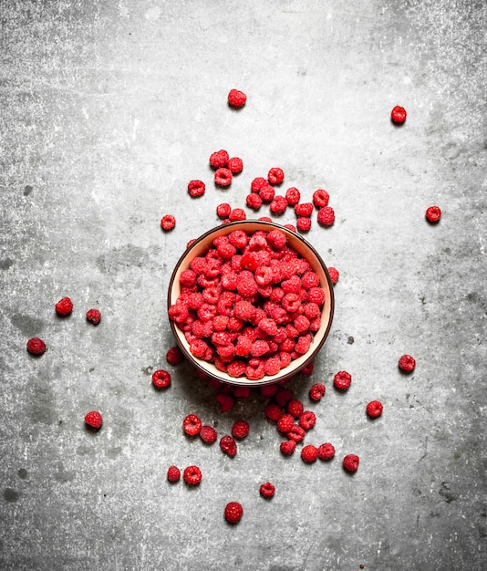 Aromatic raspberries in a bowl. On a stone table.