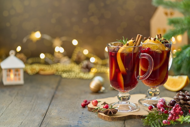 写真 木製コースターの芳香族赤ホットワイン飲料。ぼやけたボケ味の背景にクリスマスの装飾。セレクティブフォーカス、水平、コピースペース。伝統的な季節のグリューワインドリンク