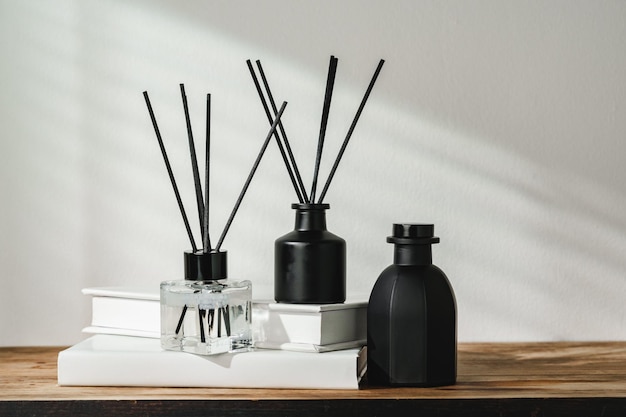 Aromatic reed diffuser on white books with shadows playing on the wall