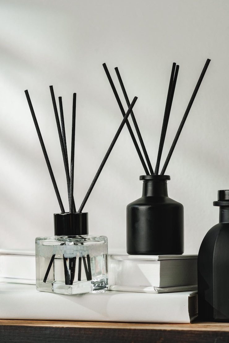 Photo aromatic reed diffuser on white books with shadows playing on the wall