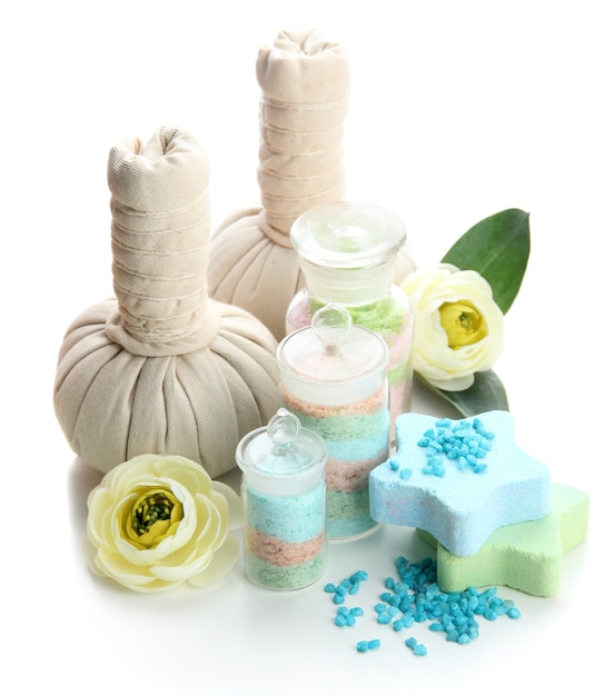 Aromatic salts in glass bottles and herbal compress balls for spa treatment, on white