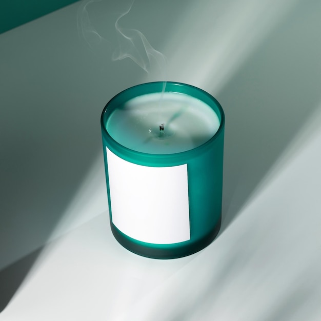 Aromatic soy wax candle in an aquamarine glass with shadows A creative image of an aromatic candle with a smoke from the wick The concept of cozy home atmosphere aromatherapy relaxation and spa