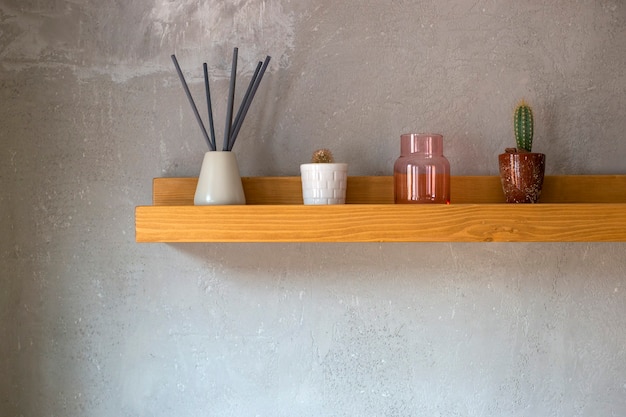 Aromatic sticks cactus succulent plant stand on a wooden shelf on the gray wall background