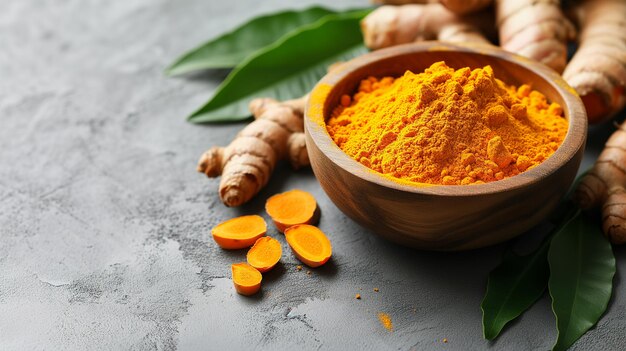 Aromatic turmeric powder and raw roots on grey table