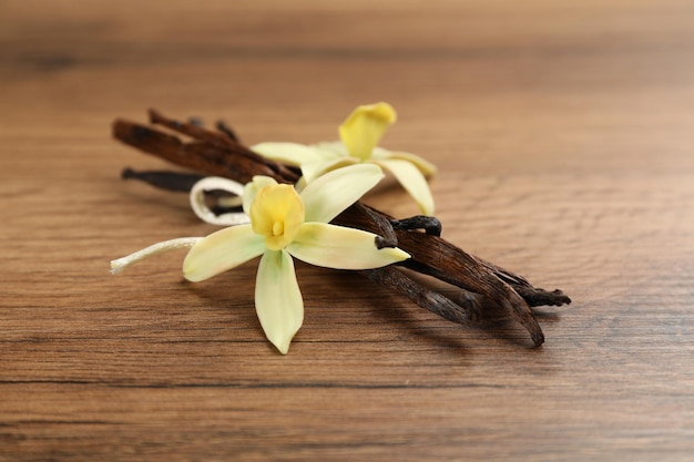Aromatische vanillestokjes en bloemen op houten tafel close-up