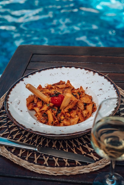 Arrabiata penne pasta aan het zwembad. Pasta penne Napoli, traditionele Italiaanse keukenschotel