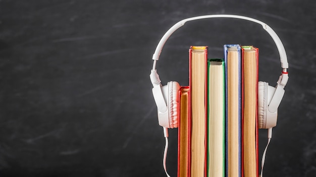 Arrangement of books with headphones with copy space