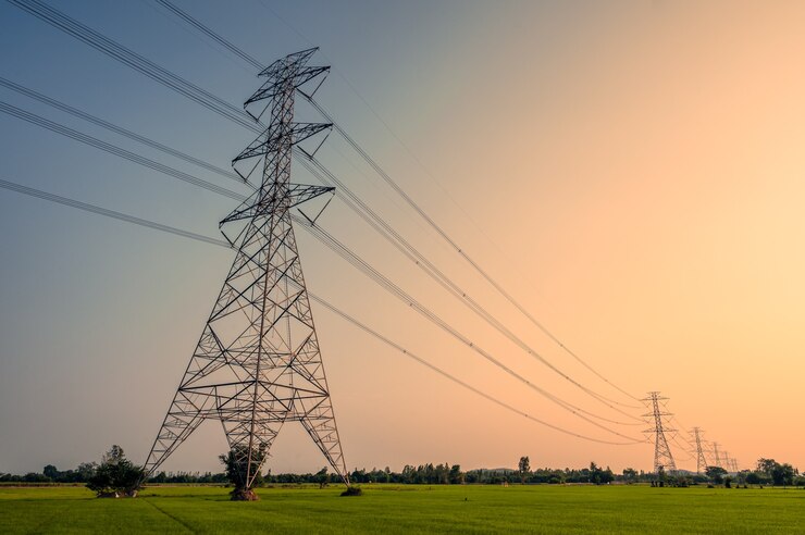Photo arrangement of high voltage pole, transmission tower on rice field in countryside at sunset