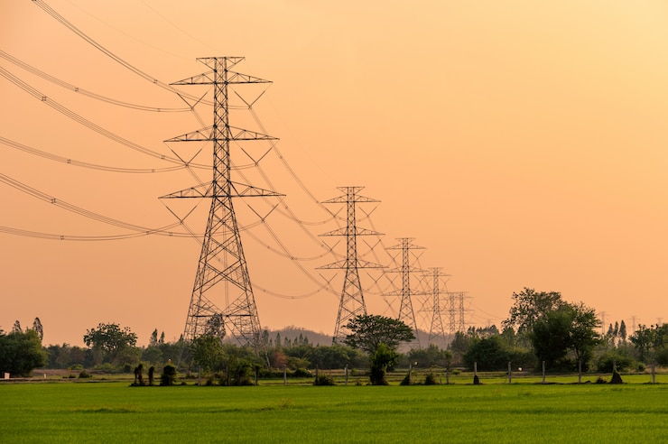 Photo arrangement of high voltage pole, transmission tower on rice field at sunset