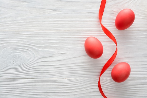 Arrangement of red Easter eggs with ribbon on wooden