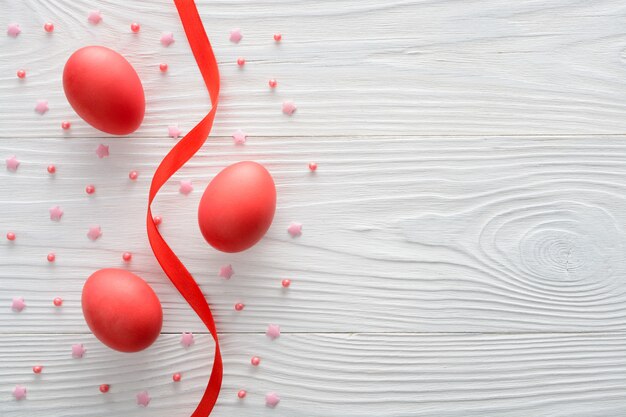 Arrangement of red Easter eggs with ribbon on wooden