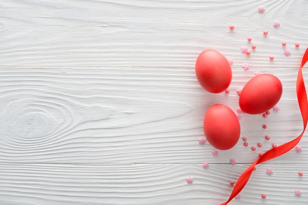 Arrangement of red Easter eggs with ribbon on wooden