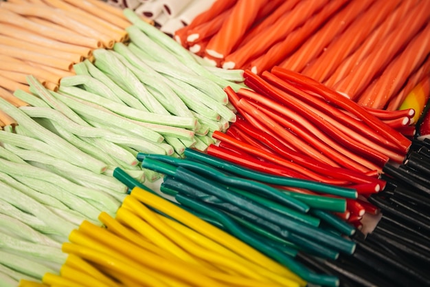 Arrangement of sweets on a market stall showing candy laces strings in a variety of rainbow colors