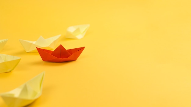 Photo arrangement with paper boats on yellow background and copy space