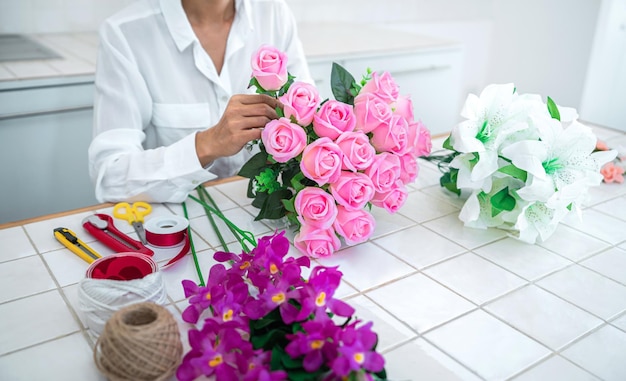 Organizzare la decorazione di fiori artificiali a casa giovane donna fiorista lavoro facendo organizzare fiori artificiali fai da te artigianato e concetto fatto a mano