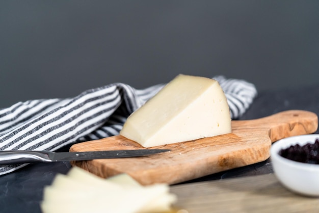 Arranging cheese, crackers, and fruit on a wood cutting board to create appetizer cheese board.