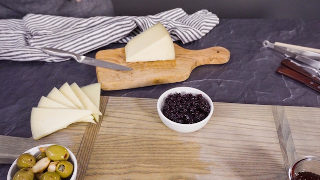 Arranging gourmet cheese, crakers, and fruits on a board for a large cheese board.