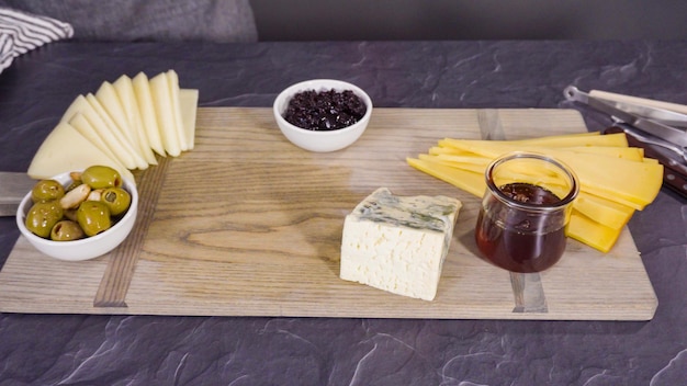 Arranging gourmet cheese, crakers, and fruits on a board for a large cheese board.