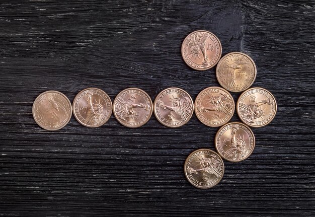 Arrow made of coins on a wooden background