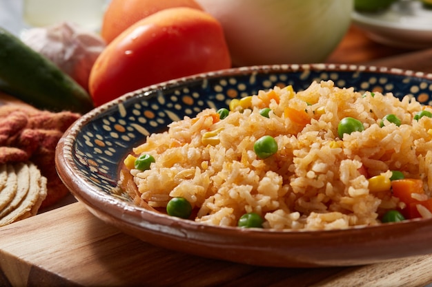 Arroz a la jardinera rojo con zanahoria chicharos en elote servido en plato mexicano