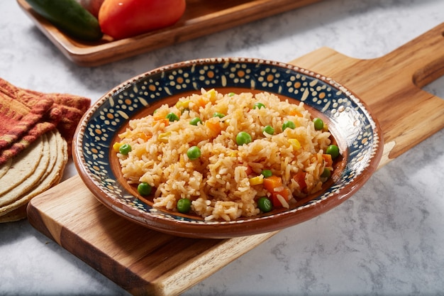 Arroz a la jardinera rojo con zanahoria chicharos en elote servido en plato mexicano