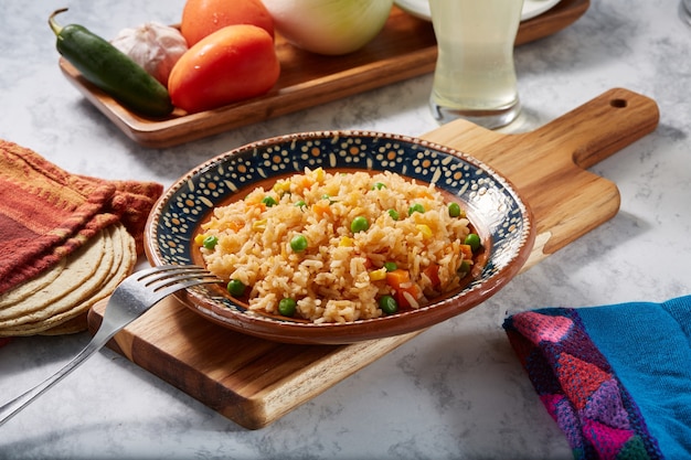 Arroz a la jardinera rojo con zanahoria chicharos en elote servido en plato mexicano