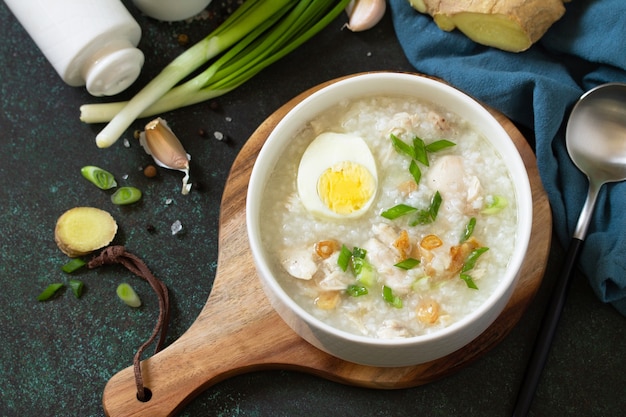 Arroz Caldo Soup Hot soup with ginger chicken rice and garlic in a bowl on a dark countertop