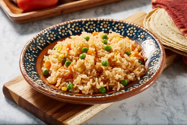 Arroz a la jardinera rojo con zanahoria elotes y Chicharos en plato mexicano