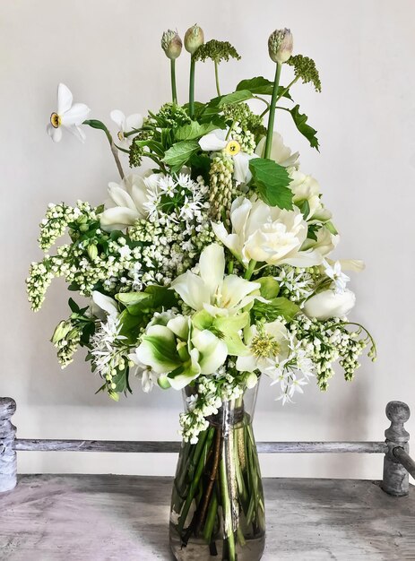 Art of arranging bouquets of flowers Romantic bouquet of white flowers in a vase on a coffee table  In composition  tulips daffodils lilacs wild garlic viburnum allium and hellebore