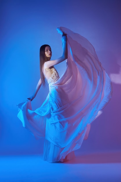 플라잉 드레스를 입은 아름다운 여성 네온 컬러 빛의 자유 개념 몸에 흐르는 드레스의 패션 스타일 바람에 펄럭이는 플라잉 드레스
