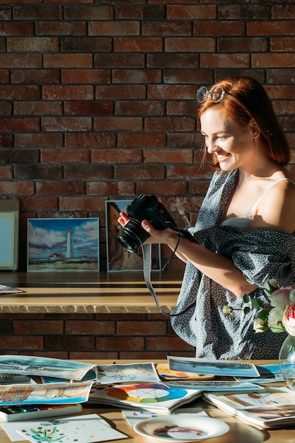 Photo art blog. studio workspace. smiling woman painter taking photos of watercolor artworks