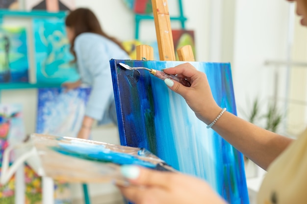 Art class and drawing concept - Woman artist working on painting in studio close-up